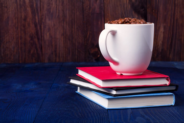 three books and mug full of coffee beans