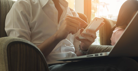 Obraz premium Man using smartphone and laptop in coffee shop, nomad worker con