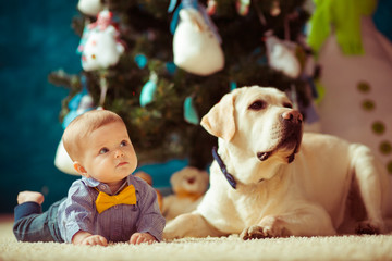 The small baby with dog lie on the carpet