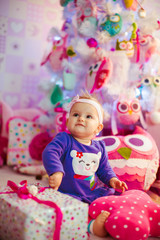 Obraz na płótnie Canvas The beautiful baby sits near gifts