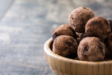 Homemade chocolate truffles in wooden bowl on wooden table

