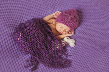 wondeful  newborn girl  in purple cap sleeping in  the bed