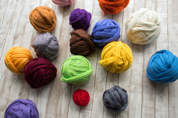 Merino wool balls in multicolor lying on wooden surface