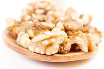 Nueces fruto seco sobre cuchara de madera sobre fondo blanco aislado. Vista de cerca y de frente