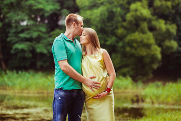 Beautiful family portrait with pregnant woman near the lake