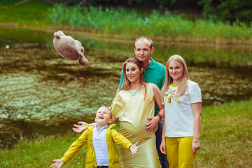 Beautiful family portrait with pregnant woman near the lake