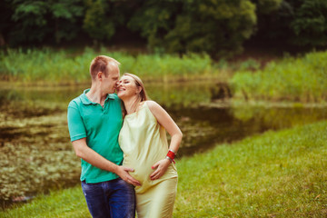 Beautiful family portrait with pregnant woman near the lake