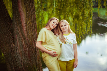 Two beautiful woman posing near the lake