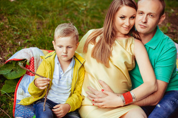 Beautiful pregnant woman with her husband and son outside