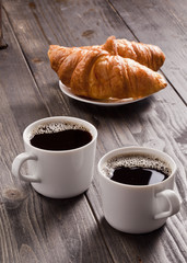 Two coffee cup an croissants.