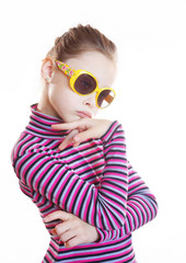 Coquettish little girl wearing striped blouse and yellow sunglasses on white background