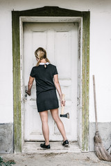 Obraz premium Creepy blond woman with axe entering into house
