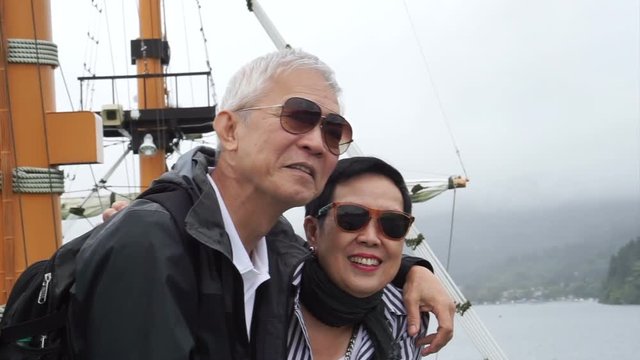 Asian senior couple travel and have boat cruising in beautiful lake 