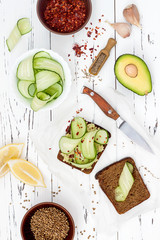 Holewheat toast with avocado guacamole and cucumber slices. Spicy avocado sandwiches on whole grain bread. Vegetarian food, healthy diet concept. Mexican cuisine. Overhead, flat lay, top view