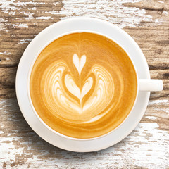 Cup of coffee with heart pattern in a white cup on wooden