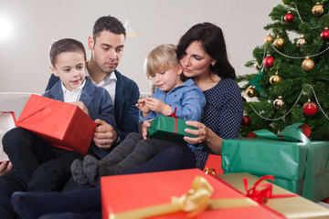 family unboxing christmas presents in front of christmas tree