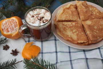 Christmas hot cocoa with marshmallows and Russian pancakes. tree branches, cinnamon, and cookies on a napkin