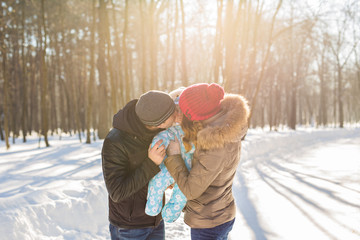 parenthood, season and people concept - happy family with child in winter clothes outdoors