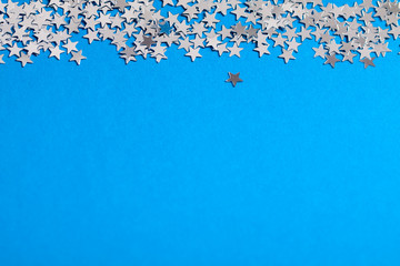 Frame of scatters little silver stars on blue background.