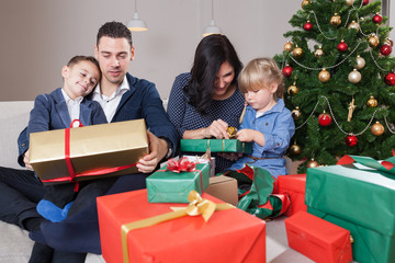 family unboxing christmas presents in front of christmas tree