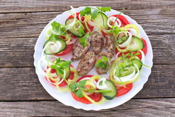 Grilled pork fillet meat and vegetables in white plate on wooden