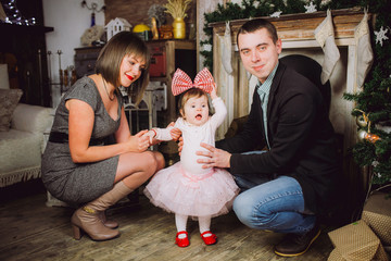 Family sitting under Christmas Tree., Mother Father and Baby Child in Decorated Room