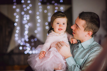 Happy Father And Baby Daughter Near By Christmas Tree And Fireplace In Christmas Evening