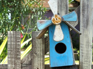 Old bird house or nest box hangs on the wooden fence.