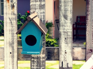 Old bird house or nest box hangs on the wooden fence.