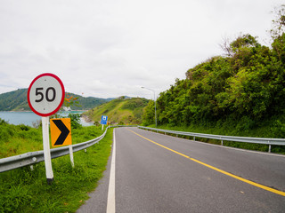 asphalt road on hill with limit speed sign board sea island at phuket Thailand