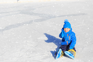 cute little boy learning to skate in winter