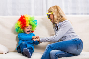 Happy mother with big sunglasses and son with wig are having fun playing.