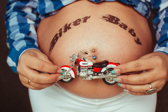 Lettering 'Biker Baby' painted over the pregnant belly