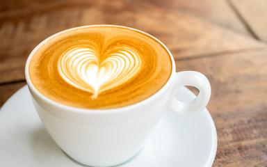 Close up white coffee cup with heart shape latte art on wood tab - obrazy, fototapety, plakaty