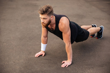 Fototapeta na wymiar Handsome young man athlete training and doing plank exercise outdoors