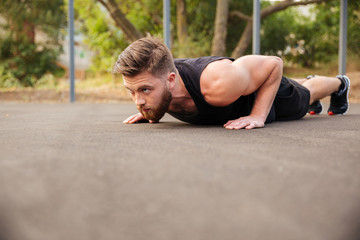 Handsome bearded sportsman doing push-ups outdoors