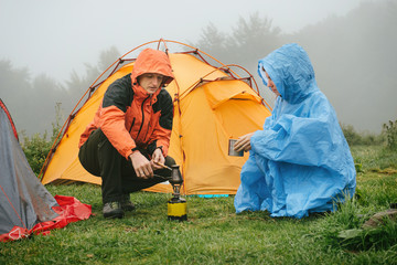 Tourists cooking coffee near tent in the mountains