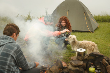 Friends having fun with dog near campfire
