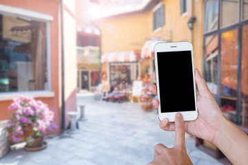 Hands woman are holding touch screen smart phone,tablet on blurred street markets old building style background.