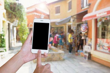 Hands woman are holding touch screen smart phone,tablet on blurred street markets old building style background.