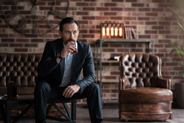 Handsome serious man taking a sip of whisky