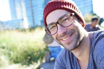 Hipster guy with eyeglasses and cap relaxing in park