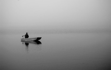 fisherman on a boat in fog - 125381569