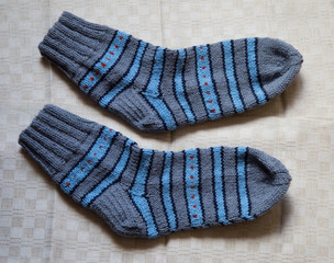 Pair of warm woolen colorful knitted socks on a linen background