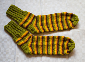 Pair of warm woolen colorful knitted socks on a linen background