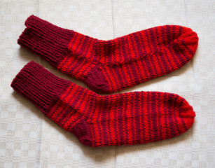 Pair of warm woolen colorful knitted socks on a linen background