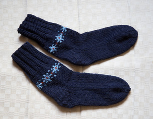 Pair of warm woolen colorful knitted socks on a linen background