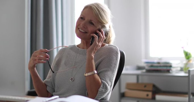 Mature business woman working on desktop computer and smartphone