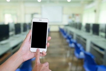 Hands woman are holding touch screen smart phone,tablet on blurred Defocused computer classroom  background.