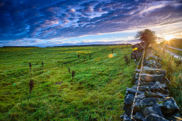Beautiful countryside landscape near Taddington in Derbyshire, UK - sunrise over a typical traditional English stone wall and farm fields with green grass